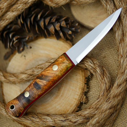 An Adventure Sworn Woodcrafter Bushcraft Knife with dyed box elder handle scales and 1/8 thick red liners