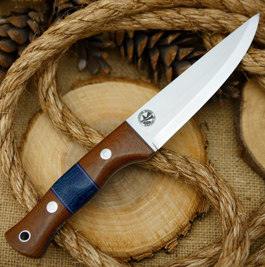 An Adventure Sworn bushcraft knife with natural brown canvas micarta handle scales and navy blue burlap spacer.